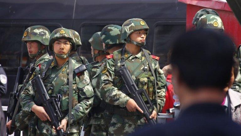 Paramilitary policemen stand guard near the exit of the South Railway Station in Urumqi