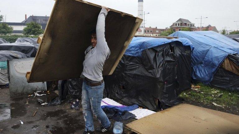 An Afghan migrant dismantles his makeshift shelter as he leaves a camp in Calais, northern France, 26 May 2014.