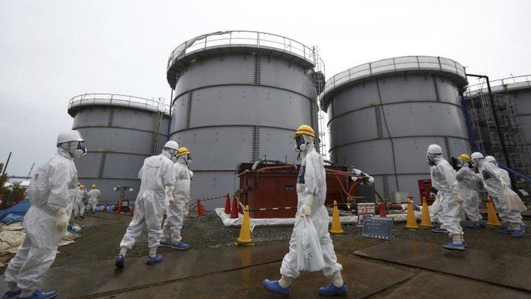 File photo: Journalists and Tepco employees wearing protective suits and masks walk past storage tanks for radioactive water at the tsunami-crippled Fukushima Daiichi nuclear power plant in Fukushima prefecture, Japan, 7 November 2013