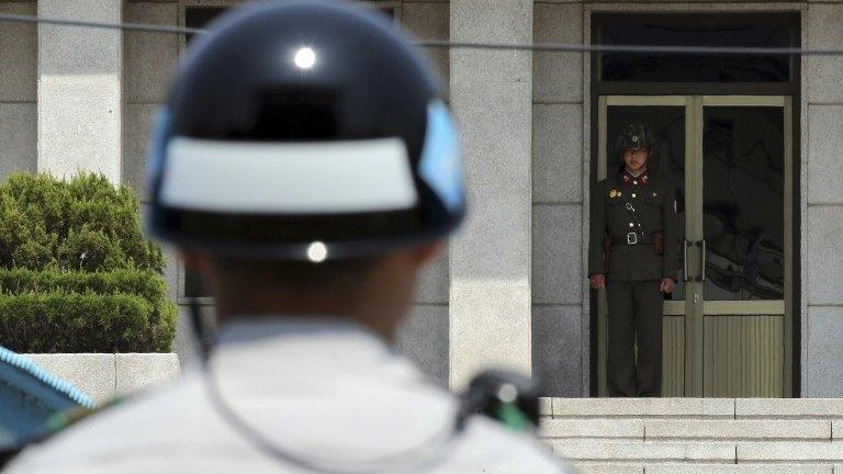 A North Korean soldier (R) looks south on the North side, as a South Korean soldier stands guard at the truce village of Panmunjom in the demilitarized zone which separates the two Koreas, May 14