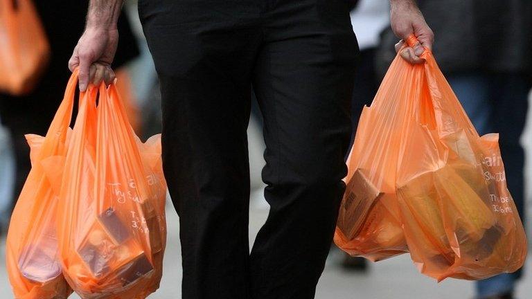 Shoppers leave a Sainsbury's store with their purchases in plastic bags