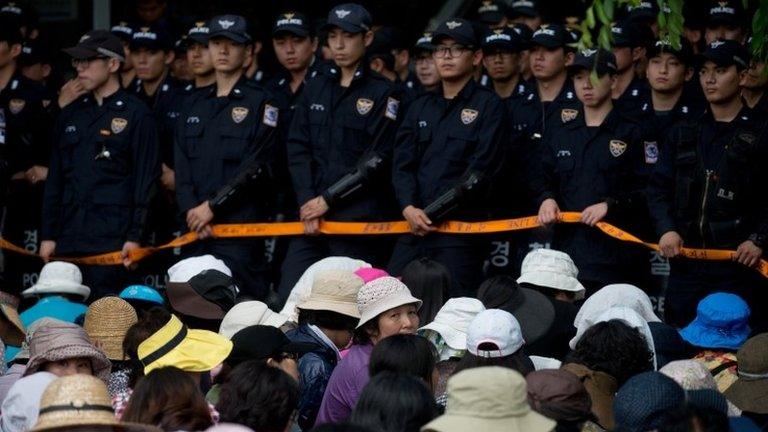 Followers sit before police outside the compound of Yoo Byung-Eun, a leading member of the Evangelical Baptist Church of Korea, in Anseong, south of Seoul on June 11