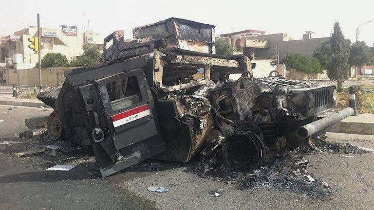 Iraqi army armoured vehicle is seen burned on a street of the northern city of Mosul, 12 June.