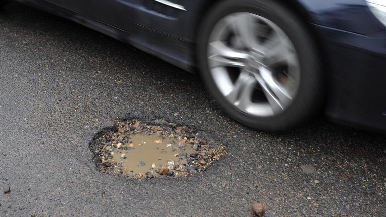 A car driving past a pothole