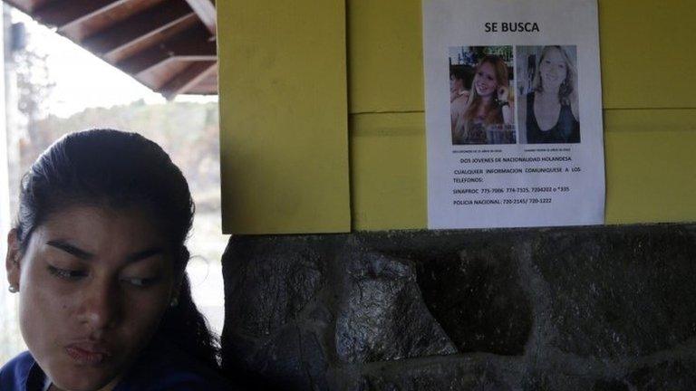 A woman stands next to a missing person flyer showing pictures of two missing Dutch women on a wall in the town of Boquete on 12 April, 2014