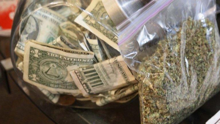 File photo: A bag of marijuana next to a money jar, Colorado, 31 December 2013