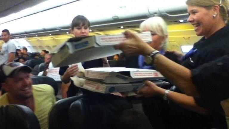 Frontier Airlines flight attendant passes out pizza to passengers aboard a Denver-bound flight diverted to Cheyenne, Wyoming 7 July 2014