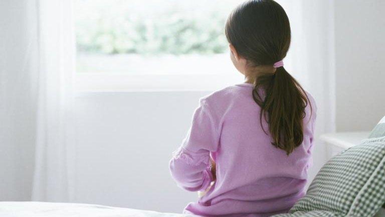 Young girl sitting on bed