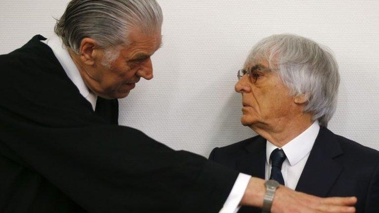 Formula One chief executive Bernie Ecclestone (R) talks with his lawyer Sven Thomas