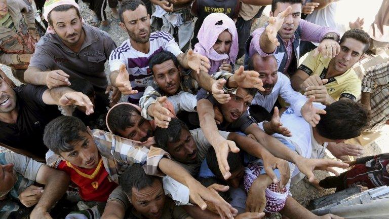 Displaced Iraqis from the Yazidi community gather for humanitarian aid at the Syria-Iraq border
