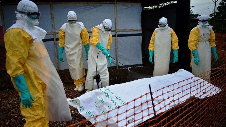 Medecins Sans Frontieres (MSF) medical workers disinfect the body bag of an Ebola victim at the MSF facility in Kailahun, Sierra Leone, 14 August 2014