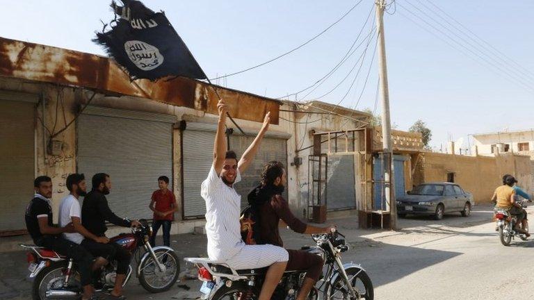 A resident of Tabqa city on a motorcycle waves an Islamist flag after the fall of the airbase