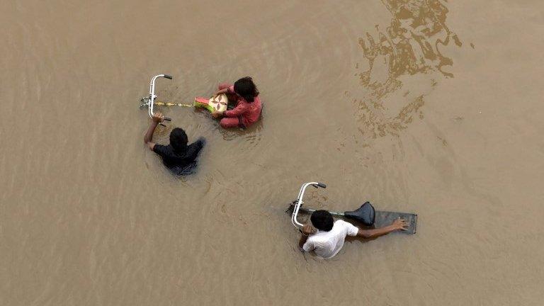 Pakistani residents wade through floodwaters following heavy rain in Lahore on September 4, 2014.