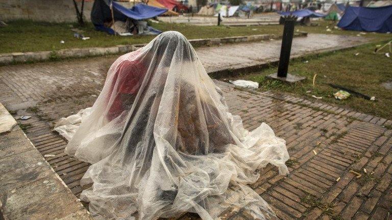 An anti-government protester covers himself with a plastic sheet during heavy rain in the morning in front of the President"s house in the Red Zone during the Revolution March in Islamabad