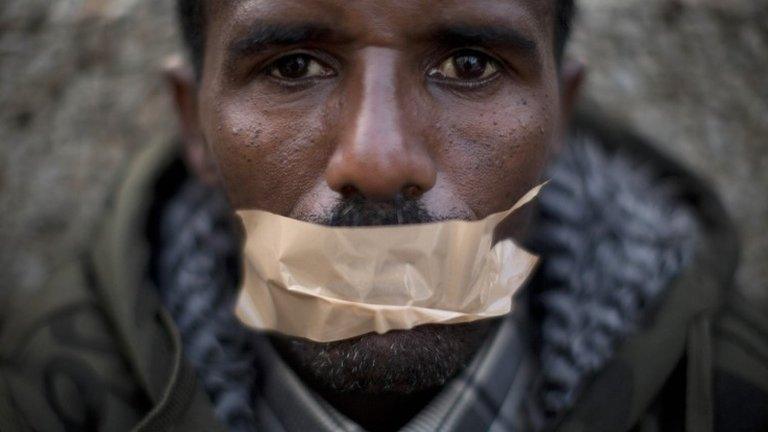 African migrant covers his mouth with tape during a protest in front of the US embassy in Tel Aviv demanding asylum and employment rights in Israel (22 January 2014)