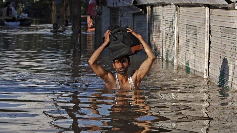 A Kashmiri man wades through a flooded street as he moves towards higher ground in Srinagar September 10, 2014.