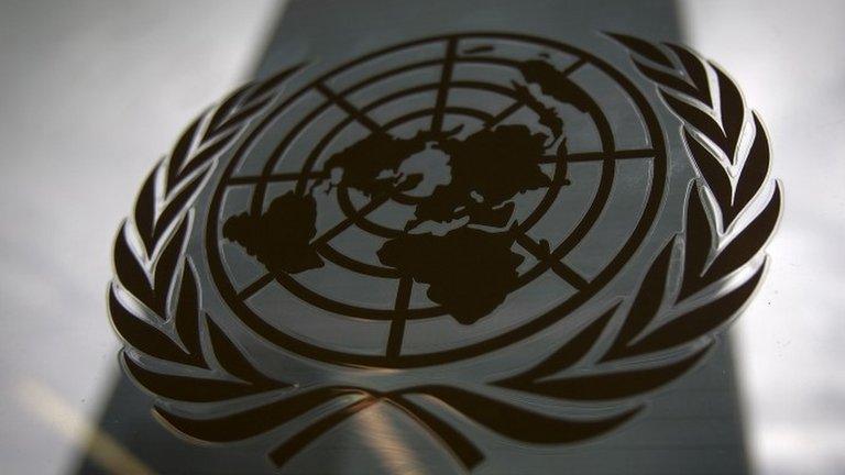 The United Nations headquarters building is pictured though a window with the UN logo in the foreground in the Manhattan borough of New York on 15 August 2014.