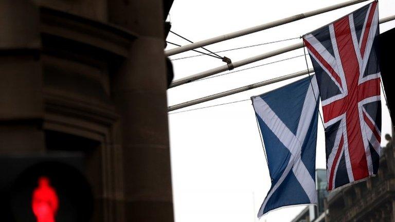 A Saltire and Union Jack flag hang side by side on a building in Edinburgh