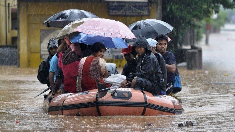 Indian residents use an inflatable boat operated by the National Disaster Response Force (NDRF) to travel through floodwaters in Guwahati on September 22, 2014