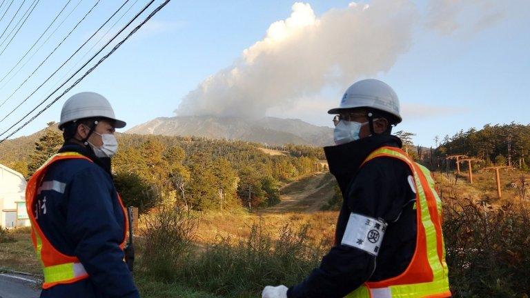 Security guards stand at the entrance of a road leading to the mountain trail of Mount Ontake in Nagano prefecture on 30 September 2014