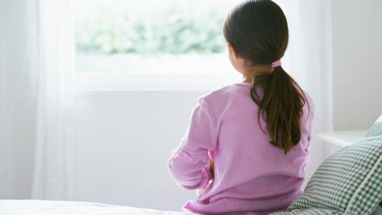 Young girl sitting on a bed