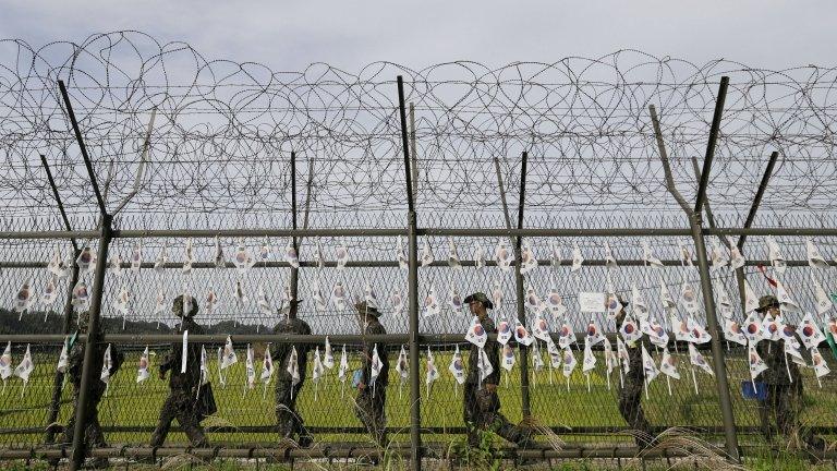 South Korean army soldiers patrol through the military wire fences with hanging South Korean national flags at the Imjingak Pavilion near the border village of Panmunjom, which has separated the two Koreas since the Korean War, in Paju, South Korea, on 17 September 2014