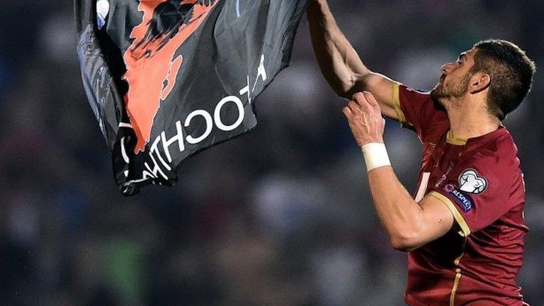 A Serbian player grabs the flag that descnded onto the pitch