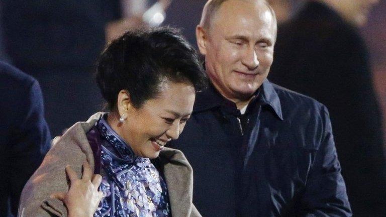 Russia"s President Vladimir Putin, right, puts a shawl on Peng Liyuan, left, wife of Chinese President Xi Jinping