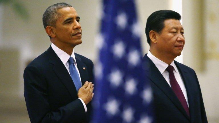 US President Barack Obama (L) and China's President Xi Jinping listen to national anthems behind a US flag during a welcoming ceremony at the Great Hall of the People in Beijing, 12 November 2014