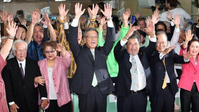 Former Naha mayor Takeshi Onaga (front C) and his supporters raise their hands in the air in celebration in Naha, the capital of Japan's southern island of Okinawa, 16 November 2014