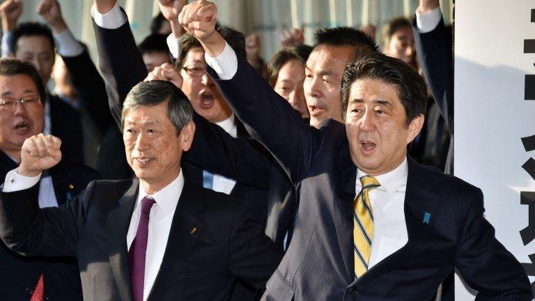 Japan's Prime Minister and leader of the ruling Liberal Democratic Party (LDP) Shinzo Abe (R) raises his fist in the air to shout with his party's lawmakers at the LDP headquarters in Tokyo on November 21, 2014 as the party opens an election campaign office.