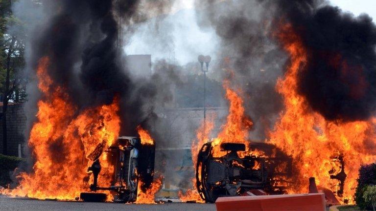 Vehicles burn at the entrance of the Guerrero Police academy after being set alight by protesters on 14 December 2014