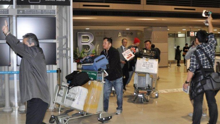 Passengers on an American Airlines flight arrive after it made an emergency landing at Narita international airport, east of Tokyo, on 17 December 2014