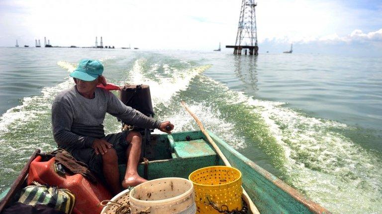 A fisherman passes oil towers on Lake Maracaibo, Venezuela, October 2010