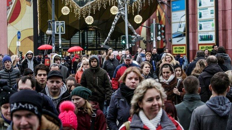 People carrying shopping bags walking in front of the Alexa Shopping Centre in Berlin