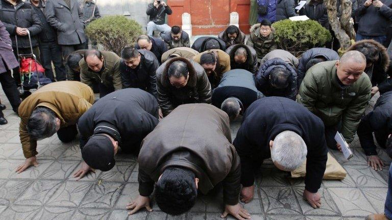 Mourners bow on the ground as they mourn for Zhao Ziyang on the 10th anniversary of his death at his house in Beijing 17 January 2015