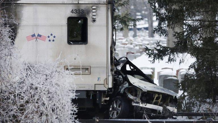 A sports utility vehicle remains crushed and burned at the front of a Metro North train 4 February 2015