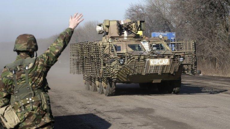 A Ukrainian government soldier salutes an armoured vehicle driving on the road towards Debaltseve, Ukraine, on Friday, as fighting continues despite a looming agreed ceasefire