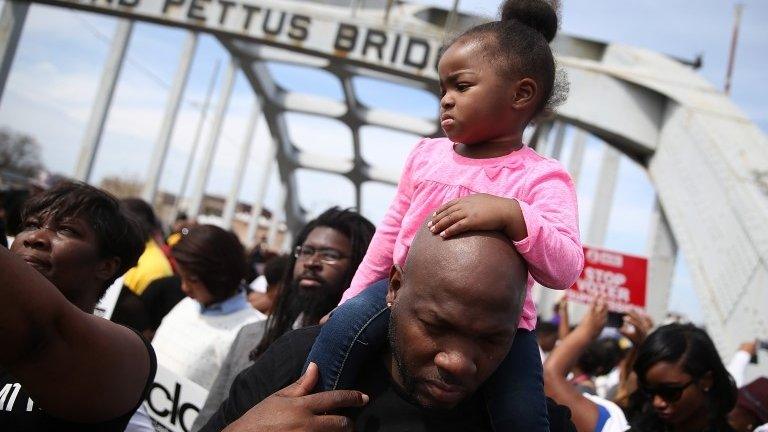 People pause for prayer as they walk across the Edmund Pettus Bridge during the 50th anniversary commemoration of the Selma march