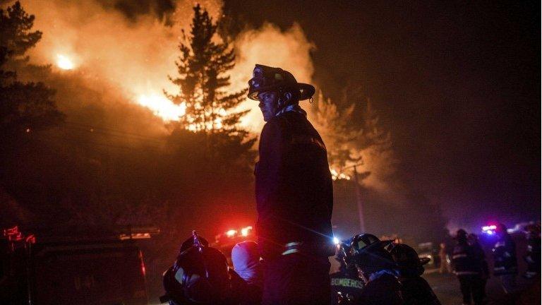 Firefighters gather to work to put out a forest fire in the hills of the port city of Valparaiso on 14 March, 2015.