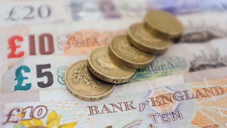 Pound coins on top of bank of England banknotes