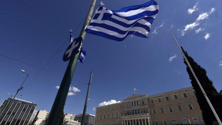 A Greek flag flutters in front of the Greek parliament