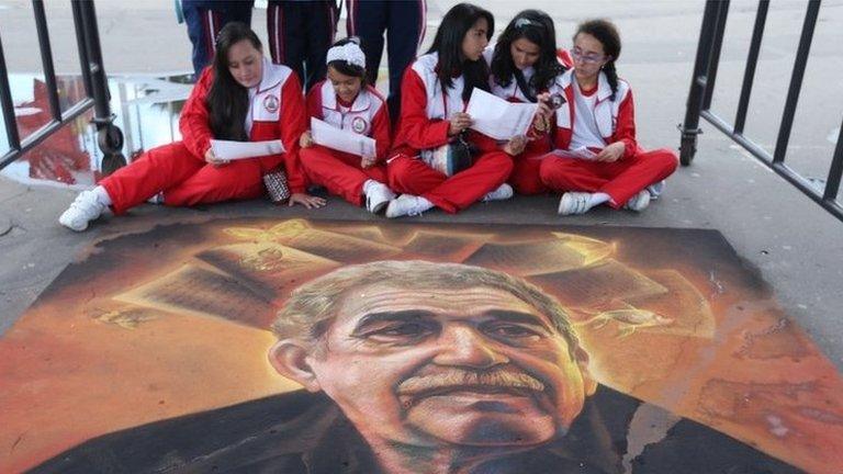 Students sit next to a chalk painting of the late Colombian novelist Gabriel Garcia Marquez in Bogota on 28 April, 2015