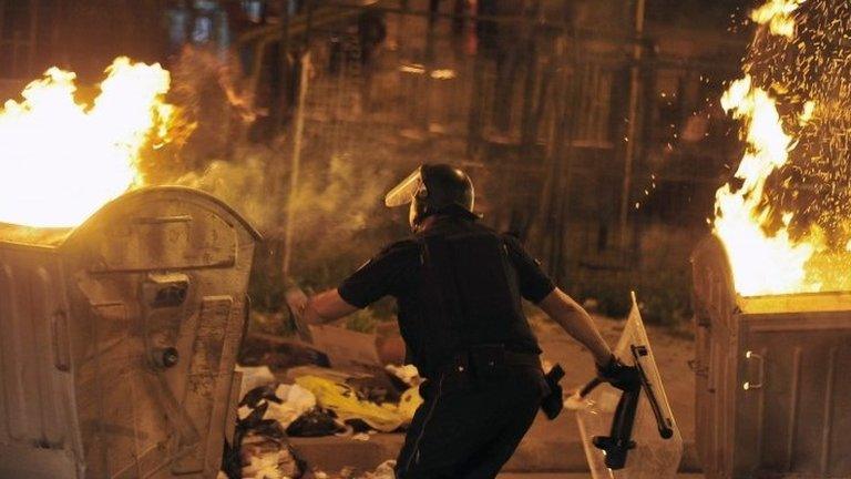 Police officer stands between two burning containers which were set on fire by protestors during an anti -government protest which escalated in the evening hours in Skopje, Macedonia on 5 May 2015.