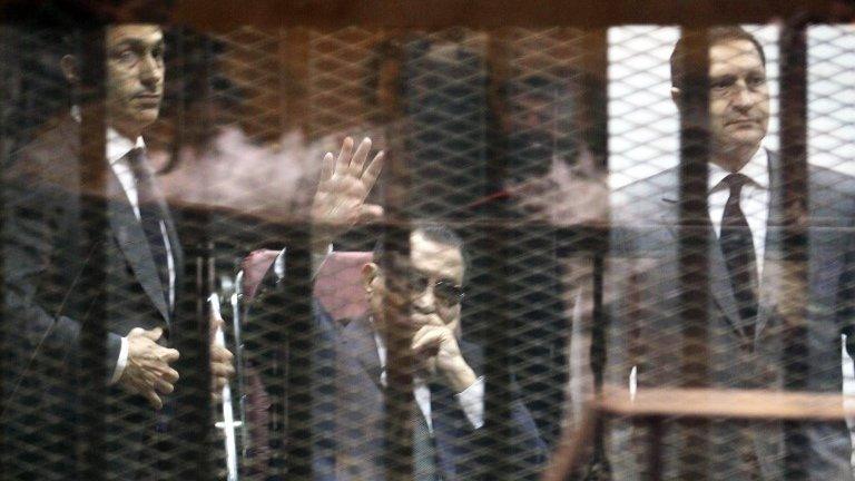 Hosni Mubarak, flanked by his sons Gamal (L) and Alaa (R), waves from the defendants' cage in Cairo, 9 May 2015.