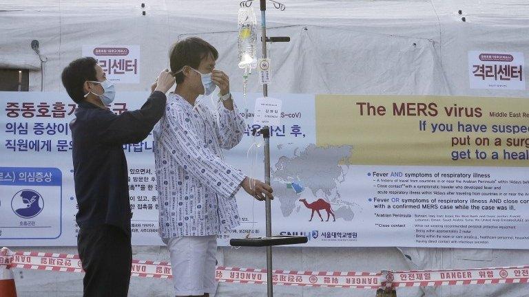 Man fitted with face mask outside a facility to examine suspected cases - 1 June