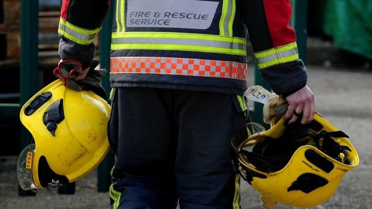 A firefighter holding two helmets