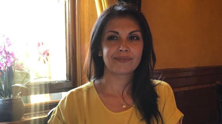 A woman with long black hair wearing a yellow top