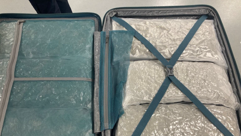 An opened suitcase stuffed with packages wrapped in plastic