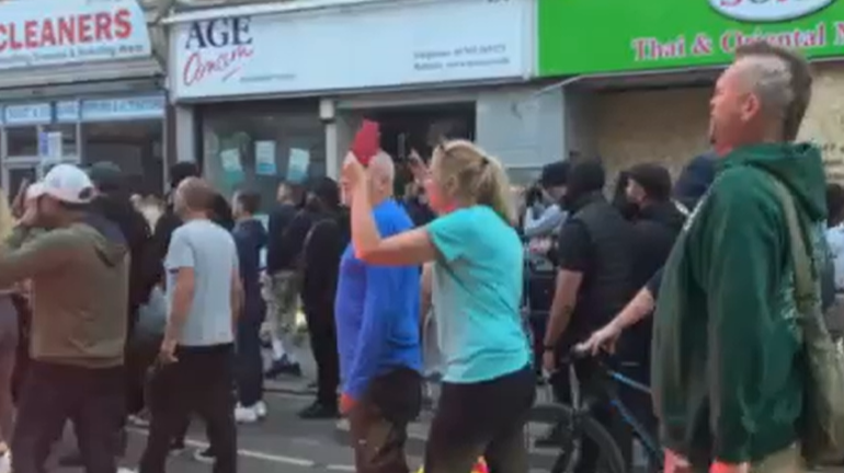 A crowd made up of people from diffrent backgrounds walking along the street